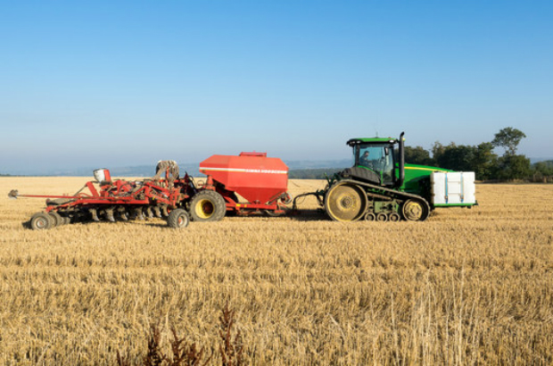 A tractor with other machinery in a stubble field