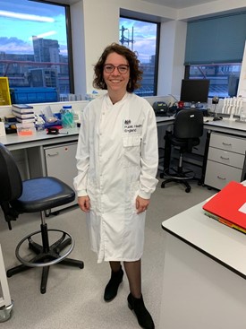 Image shows a photo of a women in a lab suit