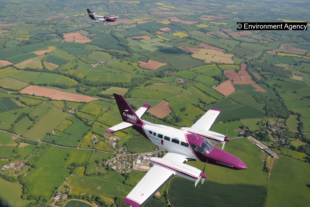 An aeroplane flies over some fields 