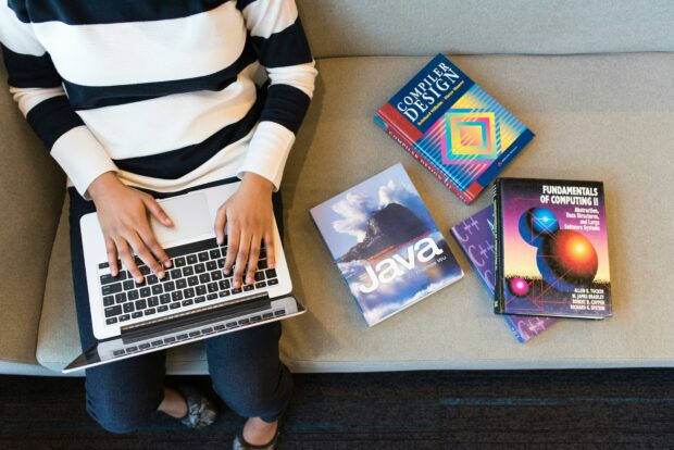 Photo of person on laptop with coding books present