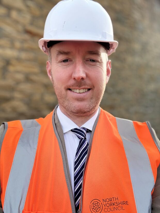 Image showing engineer James Ryan in a high vis jacket and a white helmet, facing towards camera. 